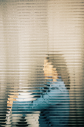 woman behind opaque glass holding her knees to show feelings of anxiety and panic